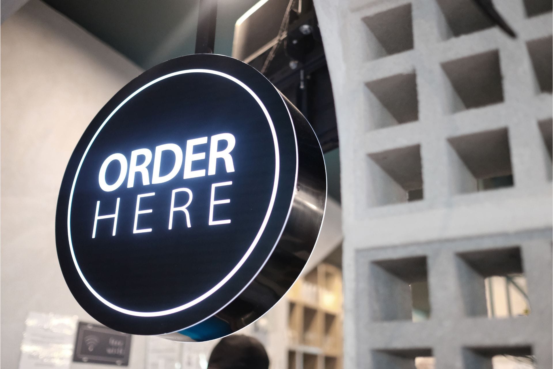 Circular sign with the text 'Order Here' displayed prominently, inviting customers to place their orders.