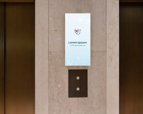 A medical-themed advertisement placed above the elevator buttons in a healthcare center, designed to capture attention and provide relevant information for visitors.